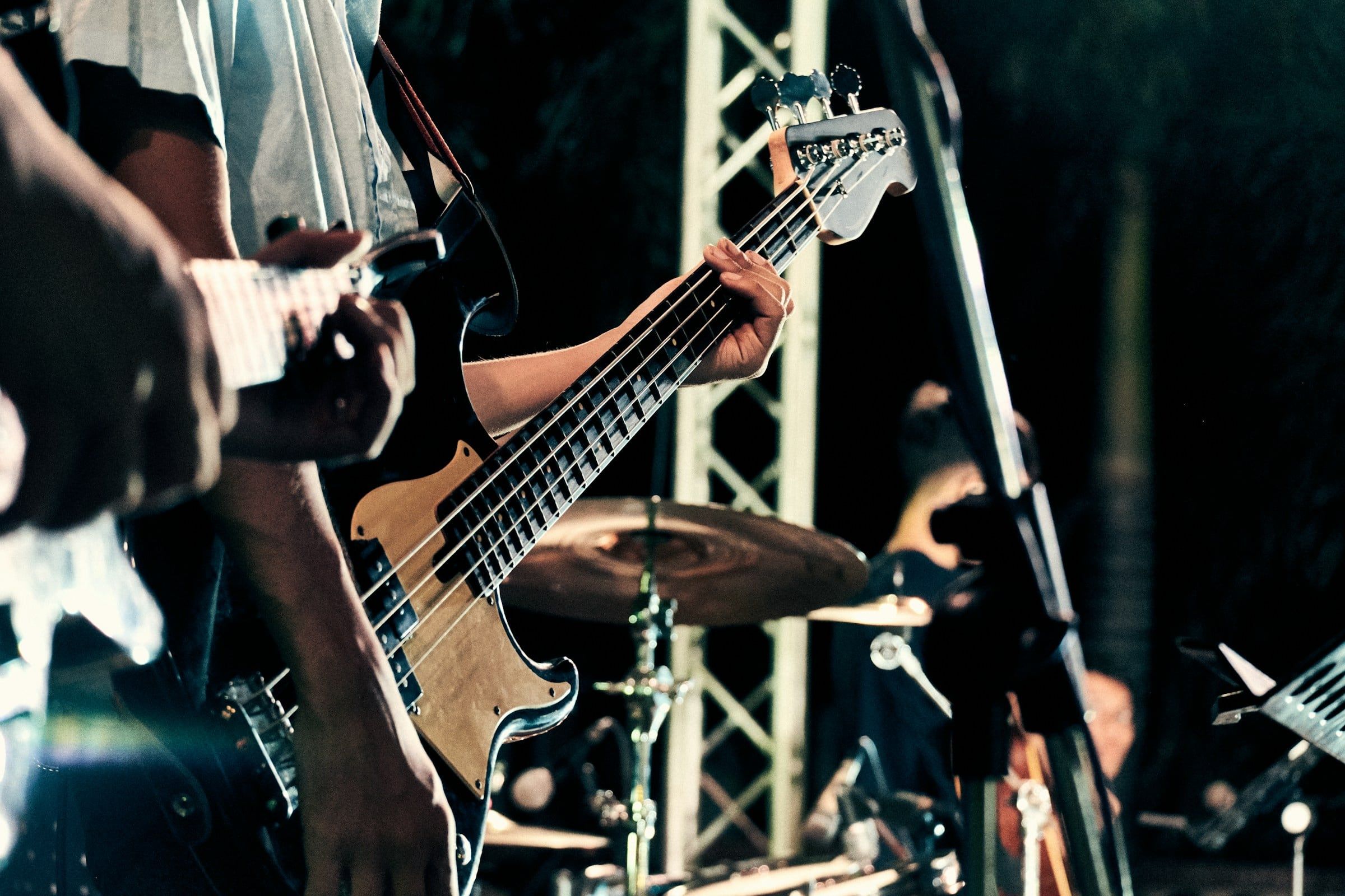 Bajista tocando en el escenario junto a la batería durante un concierto