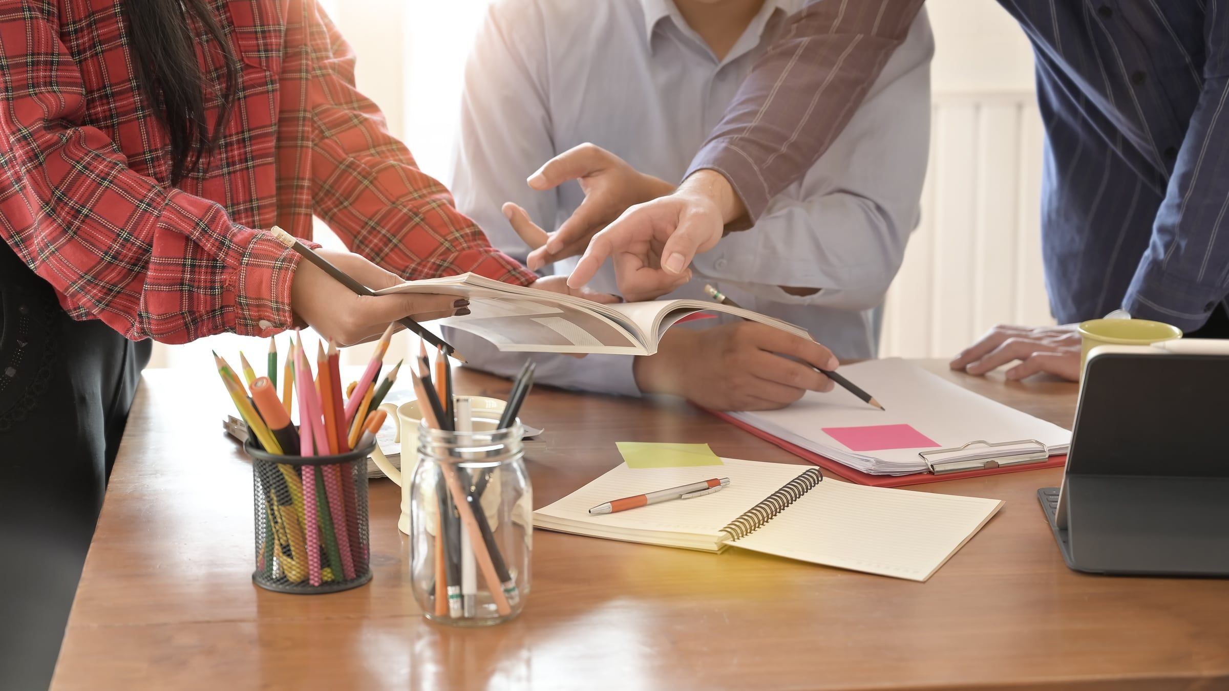 Equipo editorial revisando las páginas impresas de una publicación sobre la mesa de trabajo