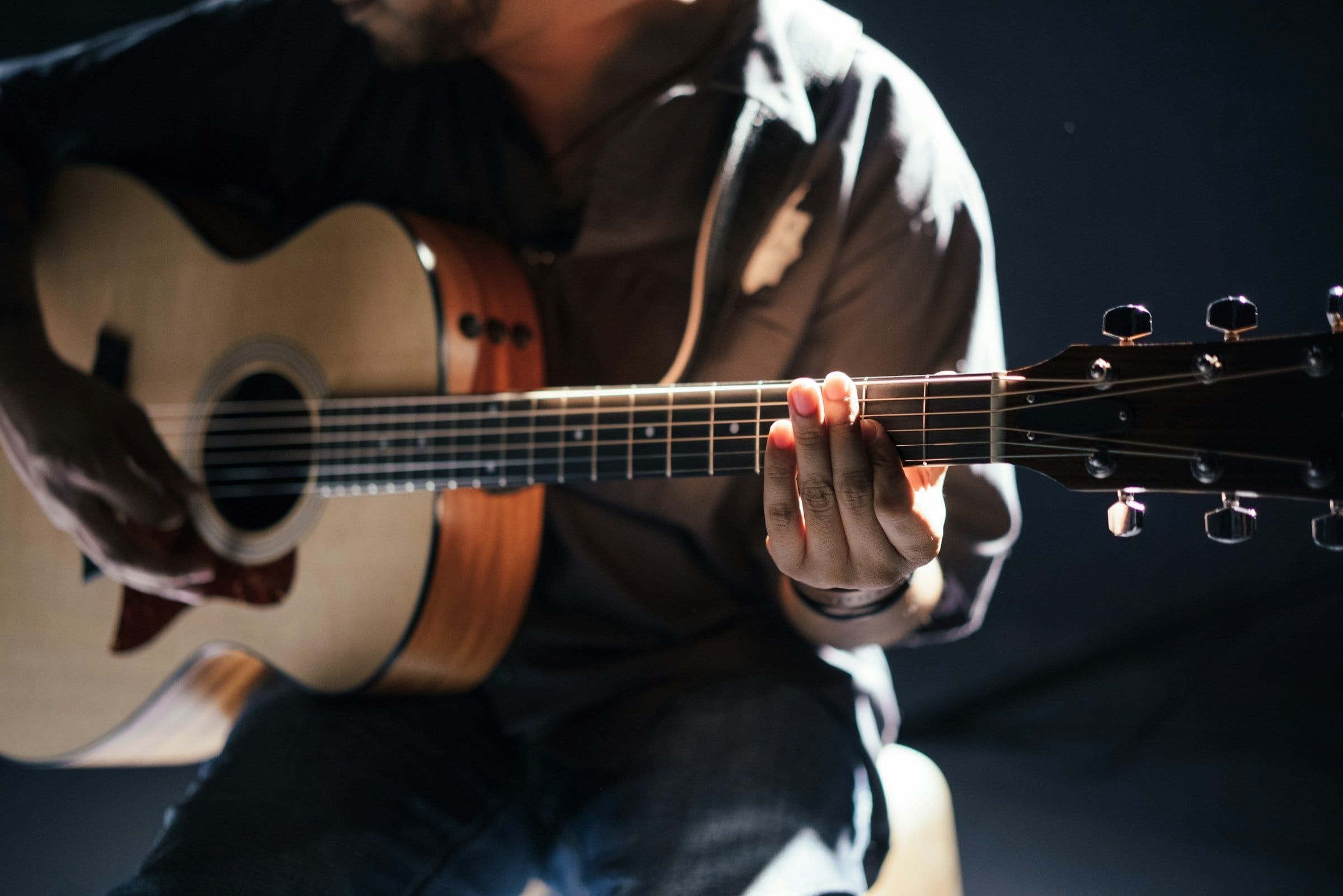 Manos tocando una guitarra acústica durante la grabación de una canción